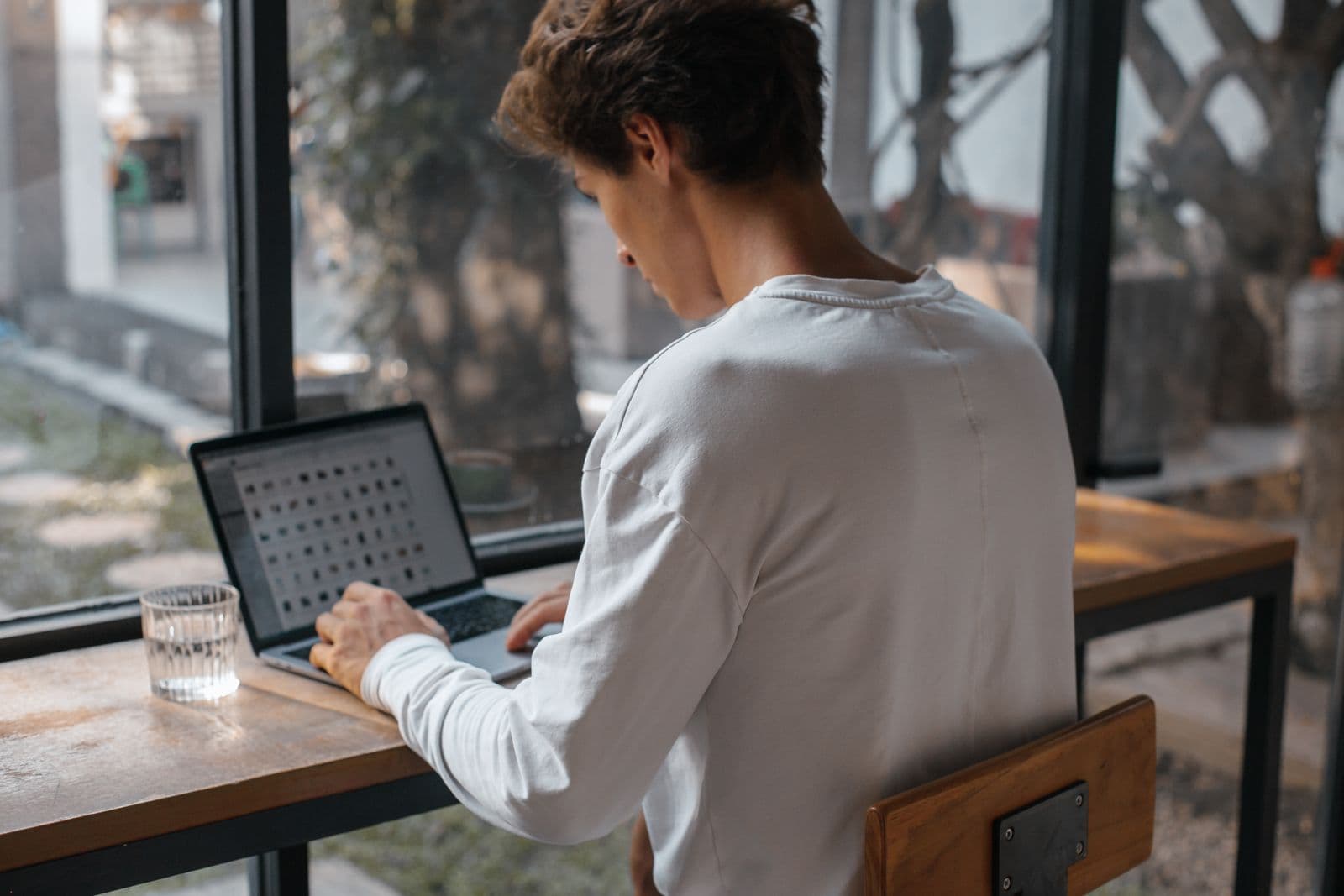 Een man werkt met een laptop bij een raam